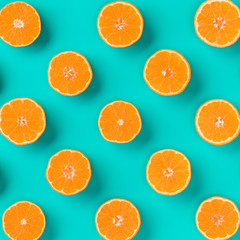 Fruit pattern of fresh mandarin slices on blue background. Flat lay, top view. Pop art design, creative summer concept. Half of citrus in minimal style. Tangerine.