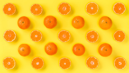 Fruit pattern of fresh mandarin slices on yellow background. Flat lay, top view. Pop art design, creative summer concept. Half of citrus in minimal style. Tangerine.