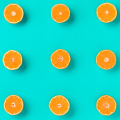 Fruit pattern of fresh mandarin slices on blue background. Flat lay, top view. Pop art design, creative summer concept. Half of citrus in minimal style. Tangerine.