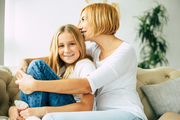 Obraz na płótnie Canvas Moms love. Happy beautiful mother and daughter spending time together, hugging and have a fun while sitting on the couch at home. Family concept