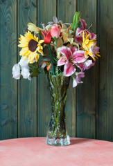 Vase of plastic flowers and wooden background