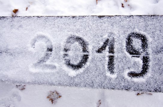 The inscription of the coming new year on the snow-covered surface of the bench