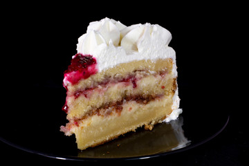 White cream cake with raspberry dressing on it with isolated black background
