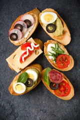 Open faced sandwich canape or crostini on dark stone background closeup. Top view.
