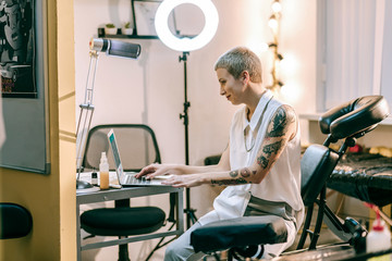 Smiling female with boyish haircut working with her laptop