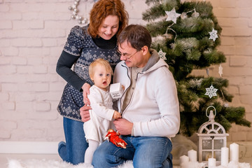 Christmas family photo: mom, dad and baby near the Christmas tree