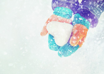 Female hands in knitted mittens with heart of snow in winter day. Love concept. Valentine day background.