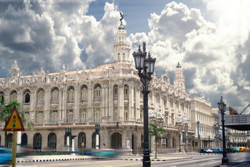 The Grand Theatre in the central of Havana in Cuba with classic american cars and tourists rushing by.