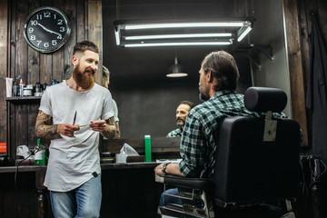 Friendly barber smiling while talking to client