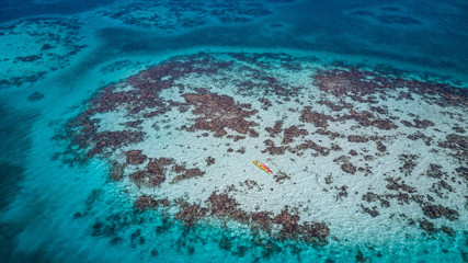 Aerial view of tropical island at Glover's Reef Atoll in Belize with two kayaks over a patch reef