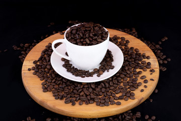 Coffee beans inside the coffee mug on wood with isolated black background