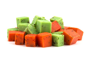 Cheese cubes of red and green color on a white background. Cheese pesto closeup on a white background.
