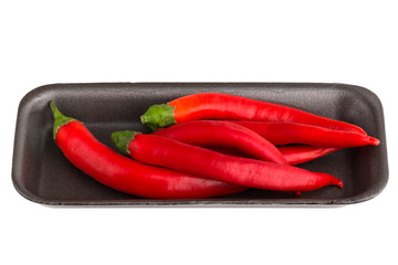 Chili peppers on a white background. A few fresh red peppers in a plastic container from the supermarket.