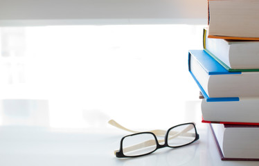 books and glasses on white table.