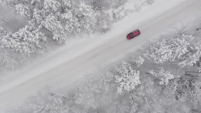 rotes Auto auf einer schneebedeckten eisigen Strasse im Winter, Glatteis, Luftaufnahme