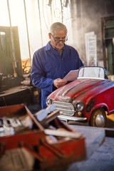 Senior man in his workshop repairing an old fashioned pedal car 