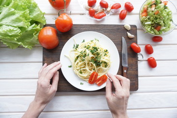 Male hands preparing ingredients for pasta on a wooden table, top view