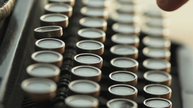 Finger typing on typewriter, close up slow motion with selective focus