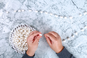Diy marshmallow garland. Guide on photo how to make a decorative marshmallow garland, threads, needles and branches with your own hands. Handmade Christmas decor. Top view. Step by step.