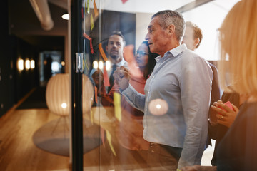 Manager reading sticky notes with his team in an office
