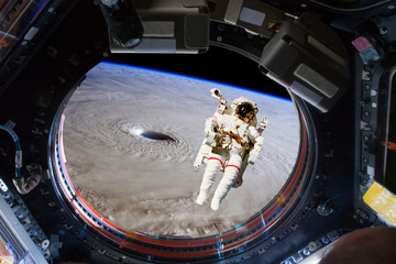 astronaut spacewalk near the earth. view from the space ship illuminator. Elements of this image...