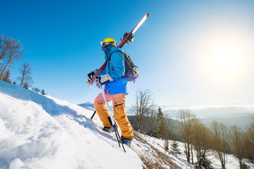 Shot of a male skier walking up the slope in the mountains carrying his skis copyspace active...