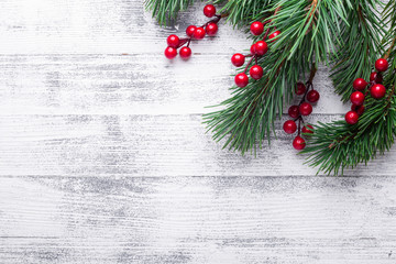 Christmas background with tree branches and holly berries. White wooden table