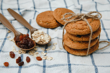 oatmeal cookies tied with twine, spoons with raisins and oat flakes