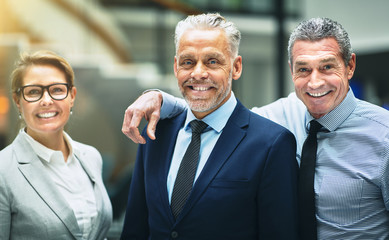 Smiling mature businesspeople standing together in an office
