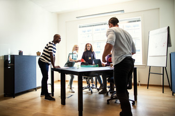 Smiling colleagues playing table tennis together in an office