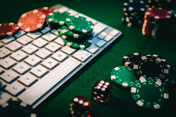 Naklejka premium Side view of a green poker table with some poker cards on a keyboard. Betting on-line concept