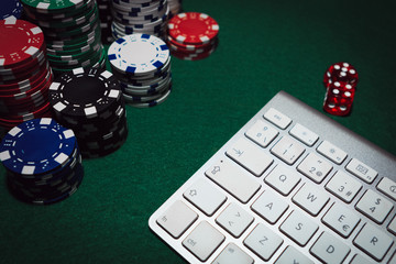 Side view of a green poker table with some poker cards on a keyboard. Betting on-line concept