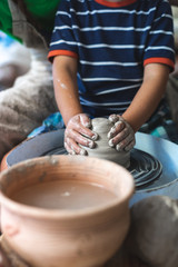 Fototapeta na wymiar Handicraft sweet moments concept. Vertical photo of small inspired kid work on master class molding product form dirty lump of clay sit indoor workspace or studio