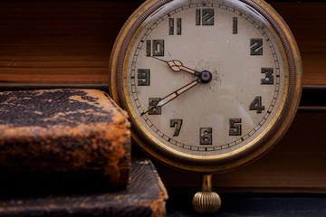 Panta rhei concept: antique pocket watch and pile of vintage hard cover books on natural stone background.