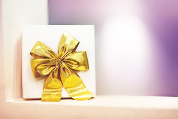Gift box with a yellow bow on a purple background.