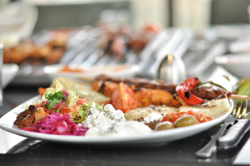 Traditional Cypriot meze and mix meat and chicken kebab table with charcoal barbecue on the table for self cooking during the eating time