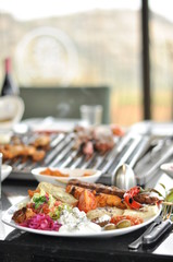 Traditional Cypriot meze and mix meat and chicken kebab table with charcoal barbecue on the table for self cooking during the eating time