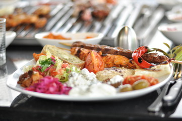 Traditional Cypriot meze and mix meat and chicken kebab table with charcoal barbecue on the table for self cooking during the eating time