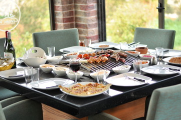 Traditional Cypriot meze and mix meat and chicken kebab table with charcoal barbecue on the table for self cooking during the eating time