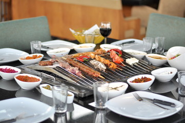 Traditional Cypriot meze and mix meat and chicken kebab table with charcoal barbecue on the table...