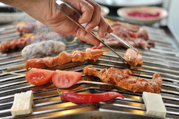 Traditional Cypriot meze and mix meat and chicken kebab table with charcoal barbecue on the table for self cooking during the eating time