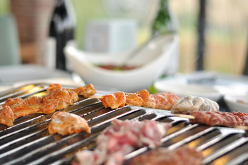 Traditional Cypriot meze and mix meat and chicken kebab table with charcoal barbecue on the table for self cooking during the eating time