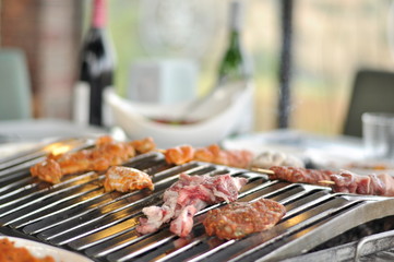 Traditional Cypriot meze and mix meat and chicken kebab table with charcoal barbecue on the table for self cooking during the eating time