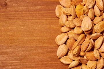 Scattered almond nuts on a brown background. Selective focus