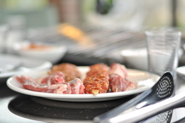 Traditional Cypriot meze and mix meat and chicken kebab table with charcoal barbecue on the table for self cooking during the eating time