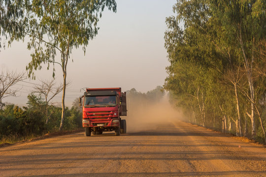 Truck speeding along dirt road across savannah and lifting large amount of dust.