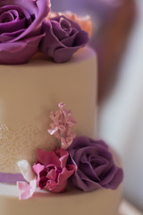 Beautiful fondant covered wedding cake decorated with edible lace and bouquet of purple lilac and...