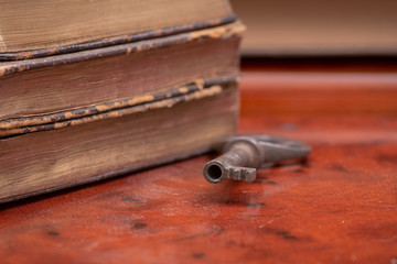Fototapeta na wymiar Pile of old vintage hard cover books and antique metallic key on wooden background