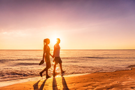 Couple walking on beach at sunset silhouettes - Romantic summer travel holidays in Caribbean destination