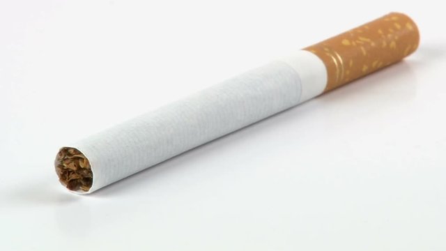 A cigarette is isolated on white, while it rotates.